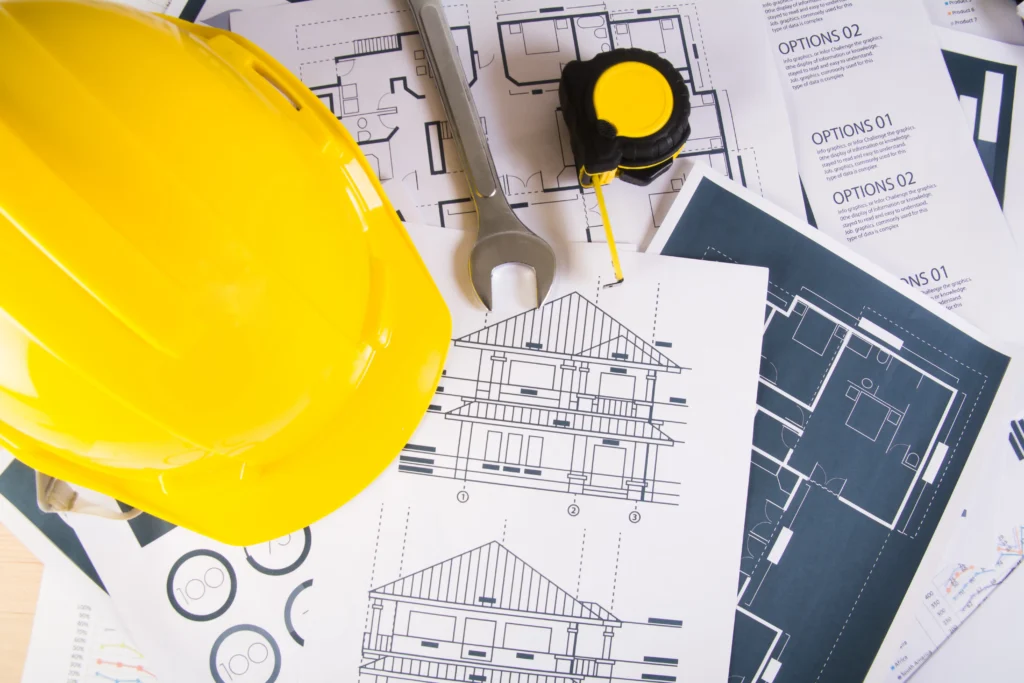 Engineer workplace with blueprints protractor safety helmet 1024x683